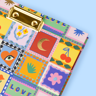 Colourful patchwork-style clipboard with a gold clip on a light blue background