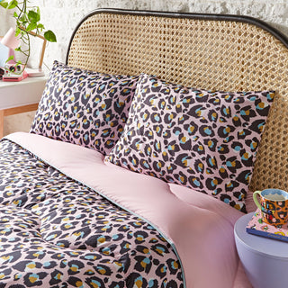 Bed with leopard print bedding and pillows in a cosy bedroom setting