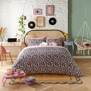 Bedroom with leopard print bedding, brick wall, and decorative elements.