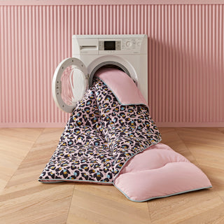Leopard print duvet in front of a washing machine against a pink wall