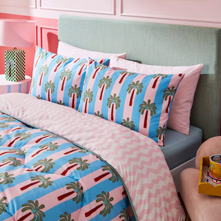 Bedroom with colourful palm tree patterned bedding and green headboard.