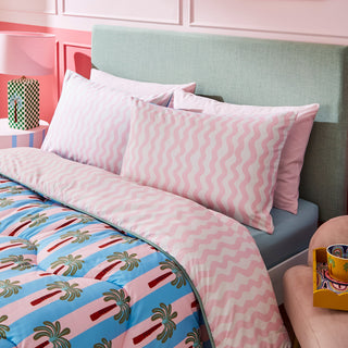 Bedroom with green headboard, palm tree patterned duvet, and framed artwork.