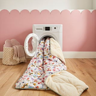 Washing machine with a colourful throw draped over it against a pink wall.